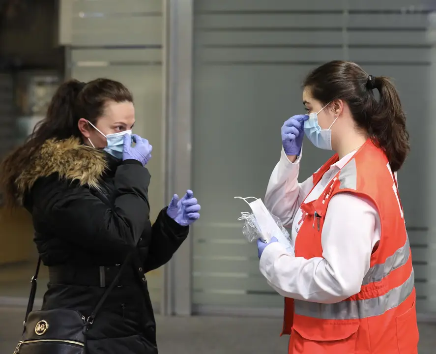 Una voluntaria de Cruz Roja da indicaciones a una pasajera sobre c&oacute;mo ponerse una mascarilla en la estaci&oacute;n de Cercan&iacute;as de Atocha durante el segundo d&iacute;a de reparto de mascarillas en el transporte p&uacute;blico por la reactivaci&oacute;n de la actividad labo - Marta Fern&aacute;ndez Jara - Europa Press - Archivo
