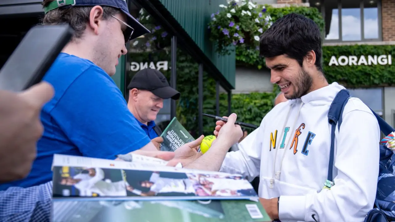Carlos Alcaraz firma aut&oacute;grafos a aficionados en la previa de la final de Wimbledon
