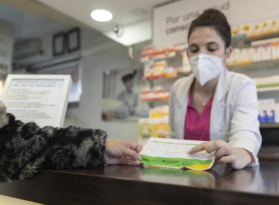 Una farmac&eacute;utica muestra un test de ant&iacute;genos a una persona (foto: Europa Press)