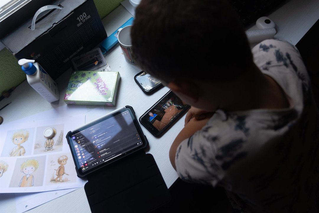 Un niño usa el teléfono móvil y una tablet (foto: EP)