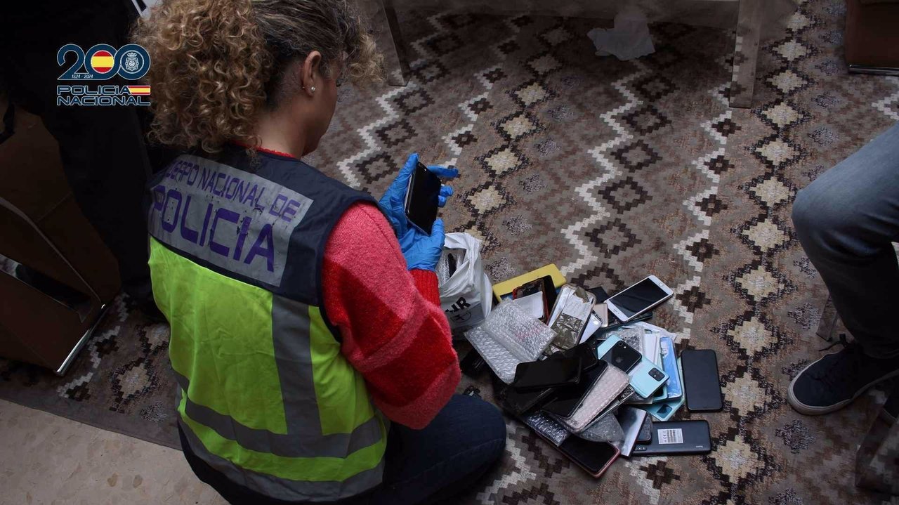 Una agente de la Policía Nacional interviene varios de los móviles hallados en uno de los registros (foto: Policía Nacional)