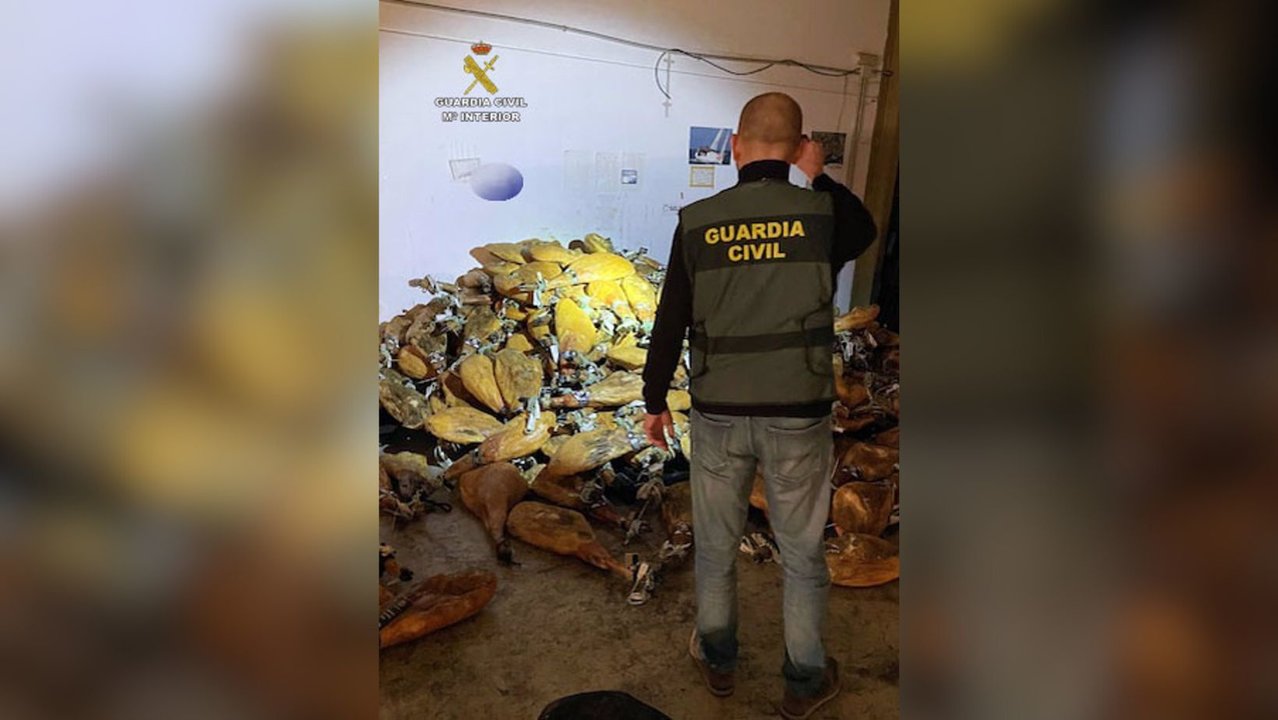 Un agente de la Guardia Civil junto a parte de los jamones robados de una empresa distribuidora de productos de alimentación de Santomera (foto: Guardia Civil)