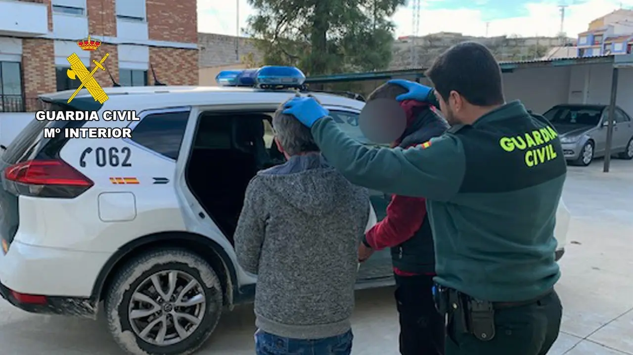 Un agente de la Guardia Civil custodia a dos de los detenidos por el atraco a un local de apuestas en Bullas (foto: GC)
