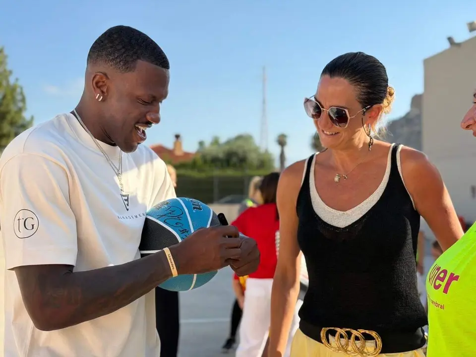 Dylan Ennis firma un bal&oacute;n a la alcaldesa de Archena en su visita a la Escuela Inclusiva (foto: Ayuntamiento de Archena)