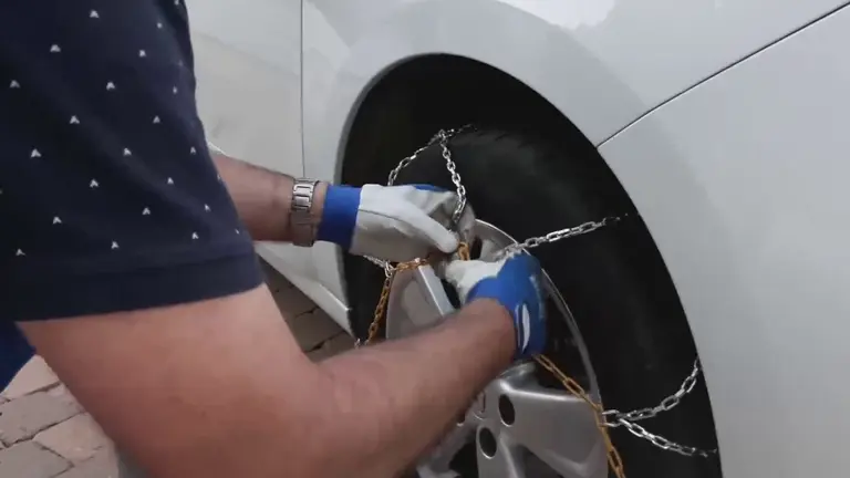 Un hombre pone las cadenas en las ruedas de su veh&iacute;culo (foto: La 7)