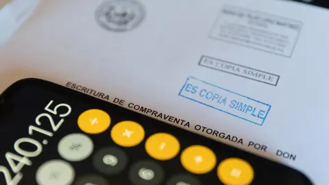 Una calculadora y una escritura de compraventa de una hipoteca (foto: Europa Press)