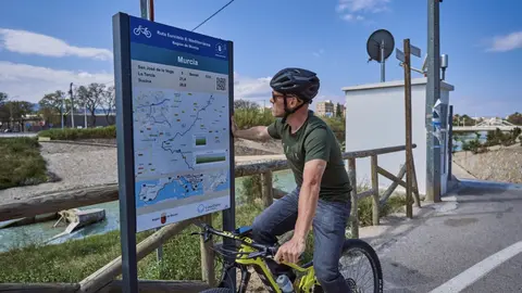 Un ciclista consulta en un poste informativo el itinerario de la Red Eurovelo en la Regi&oacute;n