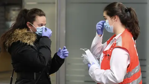 Una voluntaria de Cruz Roja da indicaciones a una pasajera sobre c&oacute;mo ponerse una mascarilla en la estaci&oacute;n de Cercan&iacute;as de Atocha durante el segundo d&iacute;a de reparto de mascarillas en el transporte p&uacute;blico por la reactivaci&oacute;n de la actividad labo - Marta Fern&aacute;ndez Jara - Europa Press - Archivo