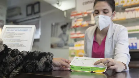 Una farmac&eacute;utica muestra un test de ant&iacute;genos a una persona (foto: Europa Press)