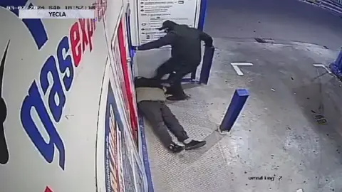 Uno de los encapuchados propina una patada a un hombre en una gasolinera de Yecla (foto: La 7)