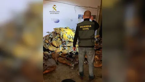 Un agente de la Guardia Civil junto a parte de los jamones robados de una empresa distribuidora de productos de alimentaci&oacute;n de Santomera (foto: Guardia Civil)