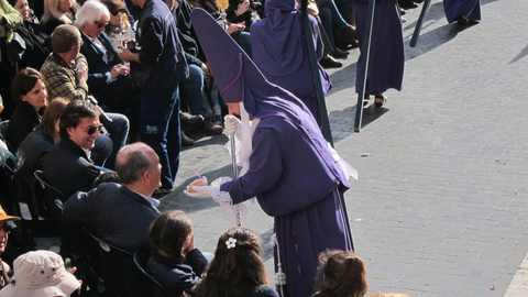 Un nazareno entregando una mona a un conocido en la ma&ntilde;ana de Viernes Santo