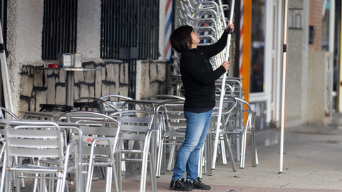 Una camarera levanta el toldo de un bar