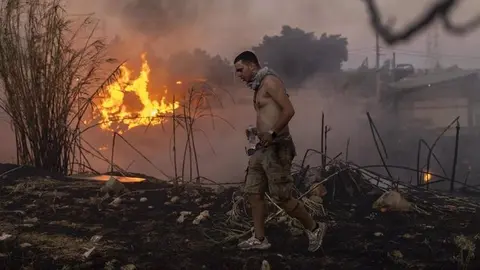Un voluntario colabora en la extinci&oacute;n de las llamas de un incendio en Penteli, a las afueras de Atenas (foto: EP)