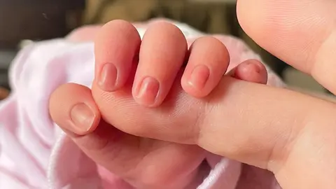 Un beb&eacute; de pocos d&iacute;as de edad coge el dedo de su madre