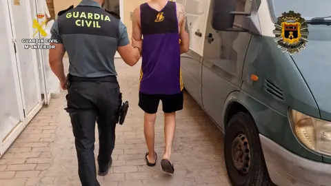 Un agente de la Guardia Civil custodia a uno de los detenidos en el marco de la operaci&oacute;n 'Anochecer' (foto:; GC)