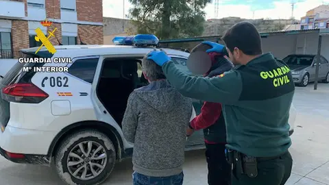 Un agente de la Guardia Civil custodia a dos de los detenidos por el atraco a un local de apuestas en Bullas (foto: GC)