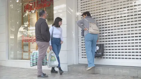 Viandantes sorprendidos ante la tienda cerrada este lunes por la ma&ntilde;ana