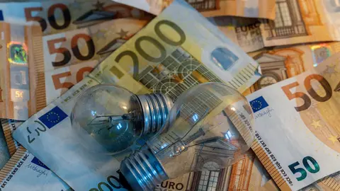 Dos bombillas sobre billetes (foto: EP)