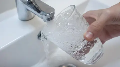 Archivo - Una persona llena un vaso de agua de un grifo