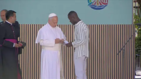 Un migrante senegal&eacute;s entrega a Le&oacute;n XIV su tarjeta de residencia como ejemplo de "esfuerzo y acogida" (foto: La 7)