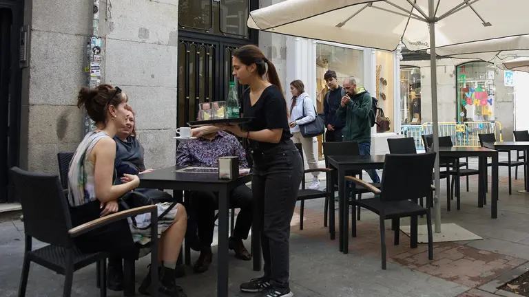 Una camarera atendiendo las mesas de un bar (foto: EP)