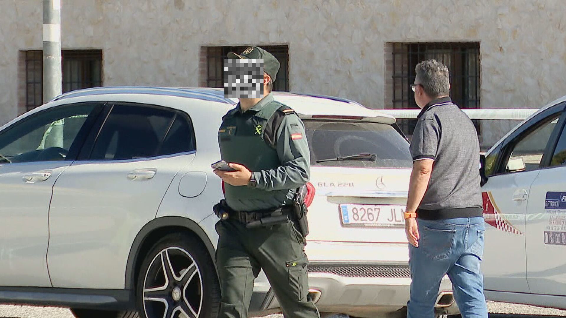 Un agente de la Guardia Civil recibe un teléfono móvil de un hombre que sale de la venta Los Collares en Abanilla (foto: La 7)